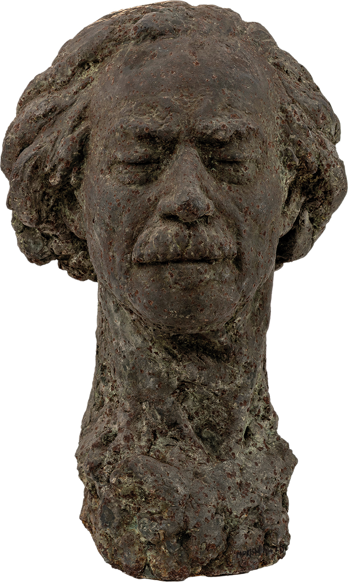 Zygmunt Kotlicki, Ignacy Jan Paderewski Zygmunt Kotlicki
1925 Mogielnica – 1998 Warszawa
Ignacy Jan Paderewski
1959 rok
Żeliwo
59 x 36 x 38 cm
Muzeum Zamoyskich w Kozłówce
MPK/SW/1470
Rzeźba przedstawia głowę Ignacego Jana Paderewskiego – ikonę polskiej kultury i historii – uchwyconą w stanie skupienia i wyciszenia. Wykonana z ciemnego, brunatnoszarego żeliwa, o nieregularnej, niemal skorodowanej powierzchni, rzeźba przywodzi na myśl obiekt wydobyty z głębi ziemi lub czasu – jakby była fragmentem jakiegoś większego, pierwotnego monumentu.
Twarz ma łagodne, a zarazem wyraziste rysy – lekko zaznaczone brwi, zamknięte powieki i spokojne usta z subtelnie zaznaczonym wąsem. Prostoliniowy nos dodaje całości dostojności, a opadające powieki i miękko wymodelowane rysy sugerują stan wewnętrznego skupienia, kontemplacji lub snu.
Włosy – bujne, falujące po bokach głowy – zostały opracowane z dużym wyczuciem formy i rytmu. Ich swobodny, niemal rozwiany układ kontrastuje z zamkniętym wyrazem twarzy, wprowadzając dynamikę do statycznego portretu. Tworzą wizualną aurę – jakby myśl, dźwięk lub wspomnienie rozchodziły się wokół tej zamkniętej, skupionej postaci.
Cała powierzchnia rzeźby – od twarzy, przez szyję, aż po podstawę – pokryta jest chropowatą, porowatą fakturą przypominającą skorodowany metal lub zastygłą lawę. To nie tylko estetyczny wybór – ta organiczna, niemal archaiczna faktura nadaje rzeźbie głębię i ciężar symboliczny.
Podstawa nie została wyraźnie wydzielona – głowa zdaje się wyrastać z masywnego, nieregularnego bloku, jakby natura sama uformowała ten portret. To zabieg, który dodatkowo wzmacnia poczucie ponadczasowości – rzeźba nie tyle przedstawia człowieka, co uosabia ideę: spokój, introspekcję, duchową obecność.