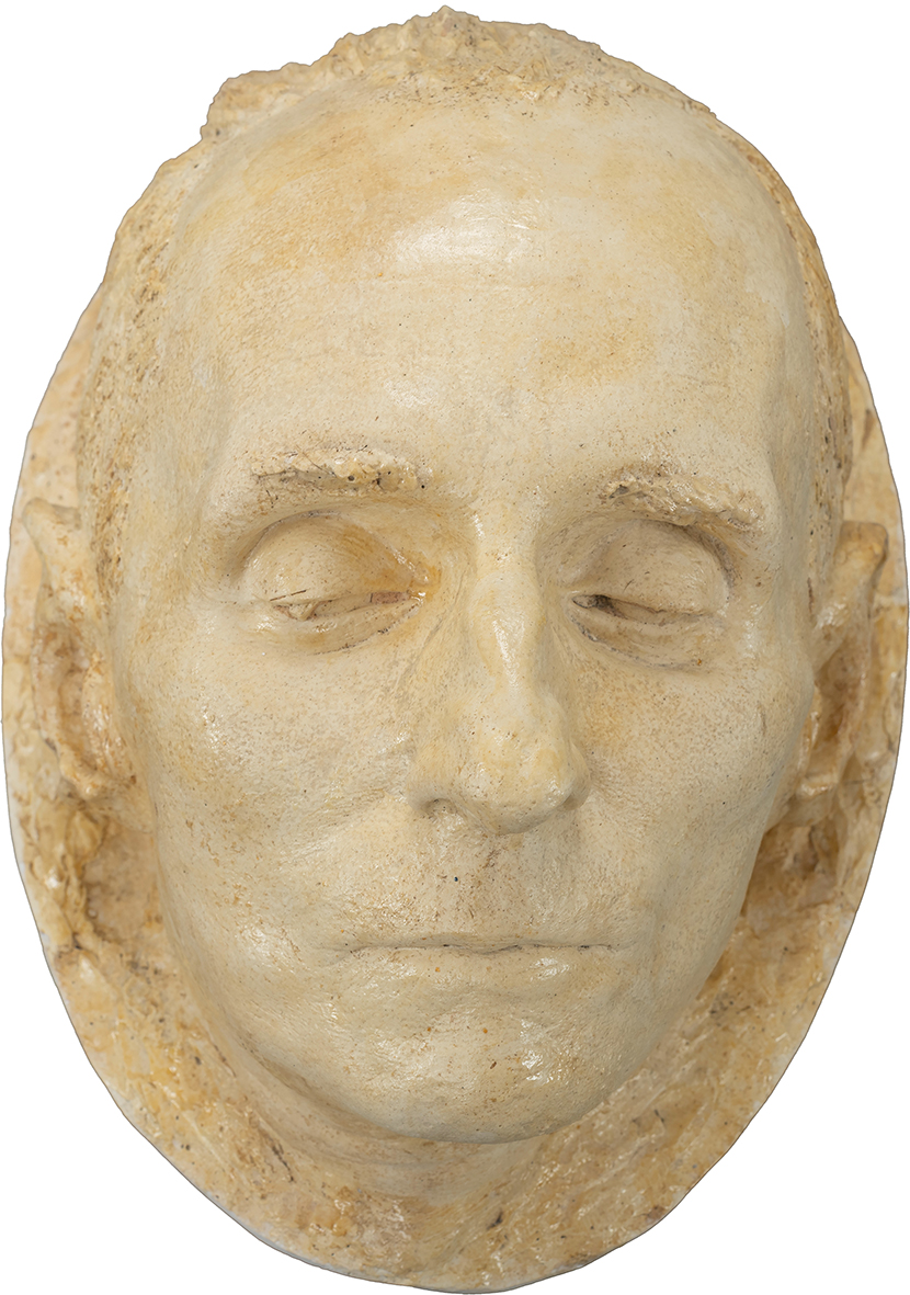 Alfon Karny, Maska pośmiertna Bronisława Linkego Alfons Karny
1901 Białystok – 1989 Warszawa
Maska pośmiertna Bronisława Linkego
powstała w 1962 roku
Gips patynowany
30 x 21 x 19 cm
Muzeum Zamoyskich w Kozłówce
MPK/SW/1110
Na zdjęciu widnieje realistyczna rzeźba twarzy – maska pośmiertna Bronisława Linkego, polskiego malarza, grafika i rysownika – przedstawiona frontalnie, ułożona jakby płasko na podłożu. Twarz spoczywa w pełnym spokoju, z zamkniętymi oczami i delikatnie zaciśniętymi ustami, które zdają się wyrażać ciszę i pogodzenie z przemijaniem.
Wykonana z jasnego, beżowego gipsu patynowanego, powierzchnia maski jest gładka, niemal aksamitna w swojej delikatności. Brak wyraźnych zmarszczek nadaje jej ponadczasową, niemal uniwersalną estetykę, podkreślając naturalistyczne, harmonijne rysy – prosty nos, wąskie usta i lekko cofniętą brodę.
Uszy są starannie wyrzeźbione, podobnie jak krótkie włosy przylegające do czaszki, ukazane drobnymi, precyzyjnymi nacięciami, które nadają całości intymny charakter.
To oblicze dorosłego mężczyzny emanuje subtelną melancholią i spokojem – nie ma w nim dramatyzmu czy bólu, raczej wyciszona kontemplacja i refleksja nad ulotnością życia. Forma maski, prosta i pełna szacunku, wzbudza w widzu czułość i zadumę, stając się symbolem pamięci i wiecznego spokoju.